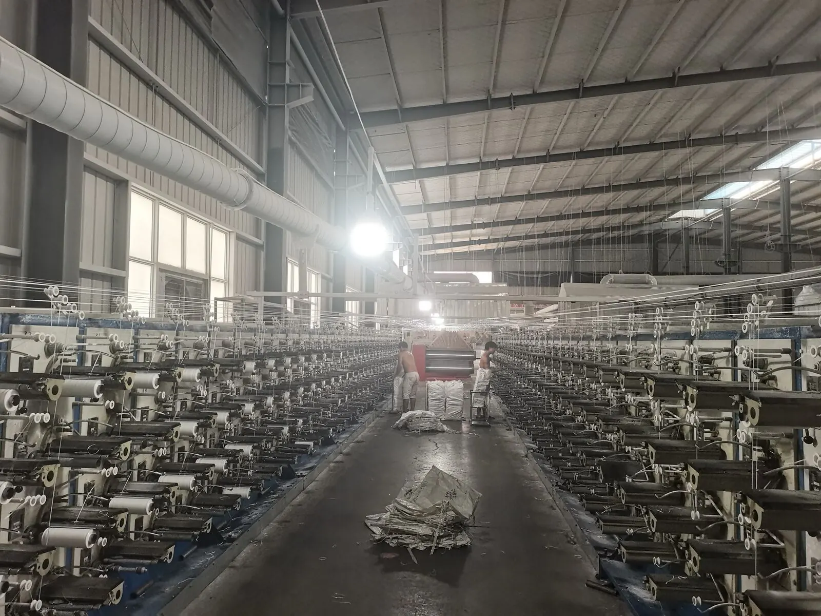 Long hall of yarn winding machines with white PP yarn bobbins